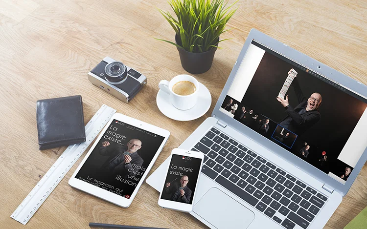 Photograph of a desk with electronic devices and a camera on it displaying Lioz Magie website