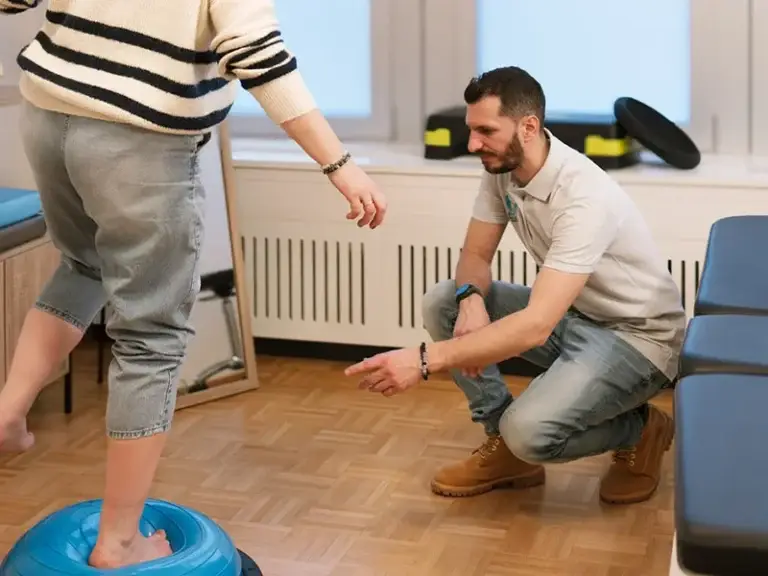 Physiothérapeute accompagnant une patiente lors d’un exercice d’équilibre en cabinet.